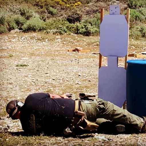 man practicing shooting from a prone position